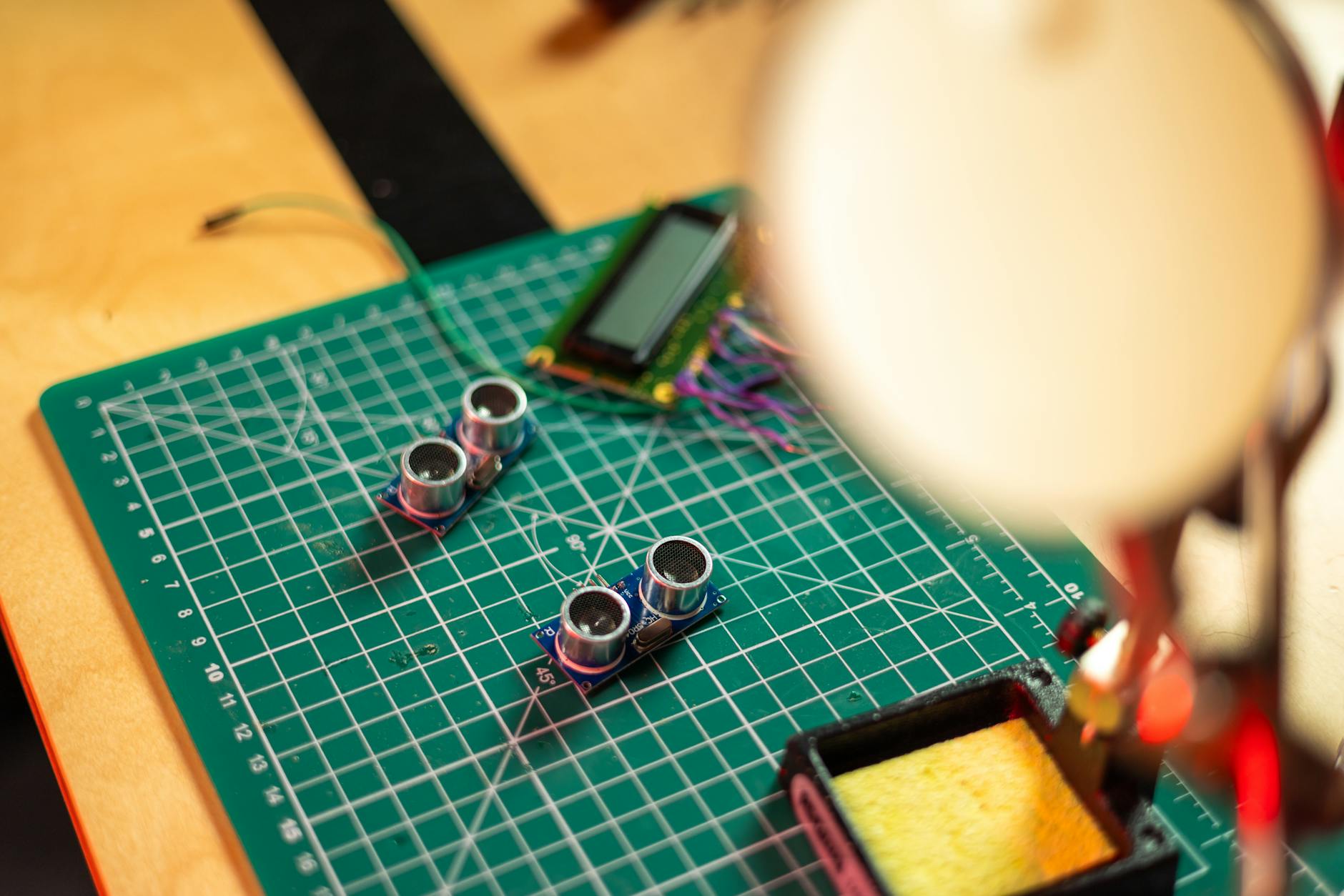 Close-up of a PCB with sensors and tools, highlighting electronics engineering setup.