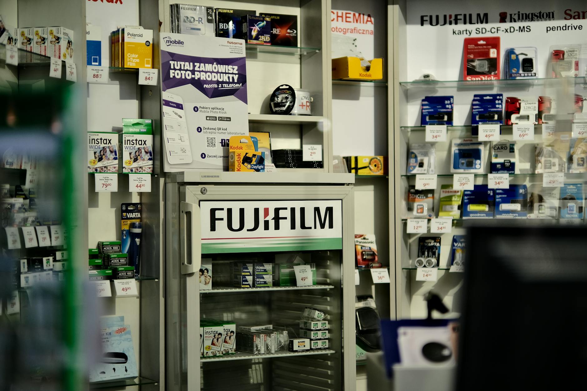 Interior view of a camera store showcasing a variety of photography products including Fujifilm items.